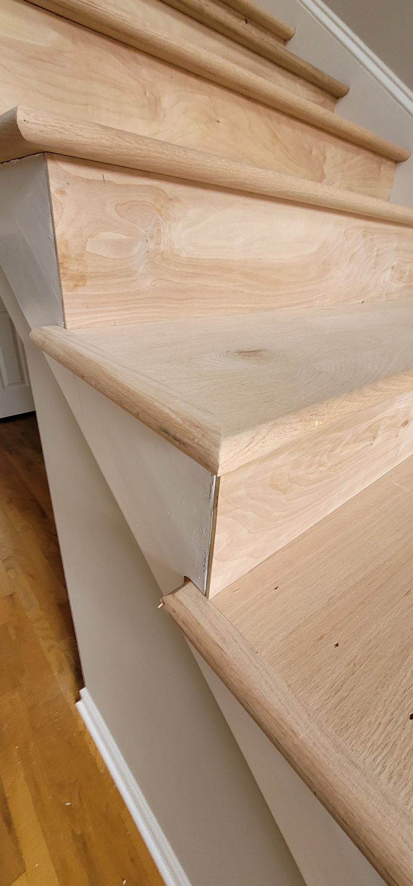 Close-up of a hand-fitted hardwood stair tread during a repair