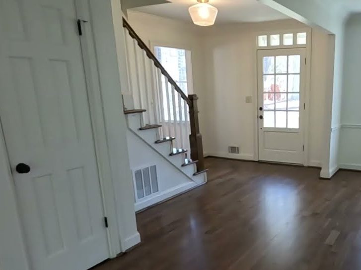 Entry hall with a staircase and a dark stained hardwood floor, hardwood installation in Roswell, GA