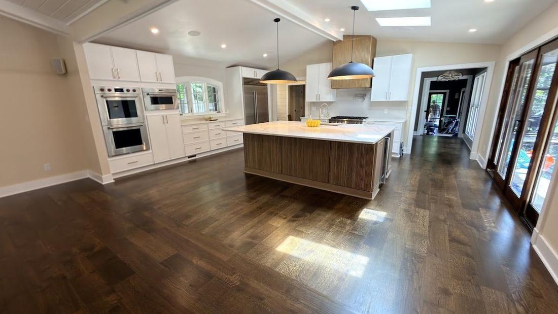 Dark-stained white oak floor running through an open modern kitchen, refinished by The Hardwood Guys in North Metro Atlanta