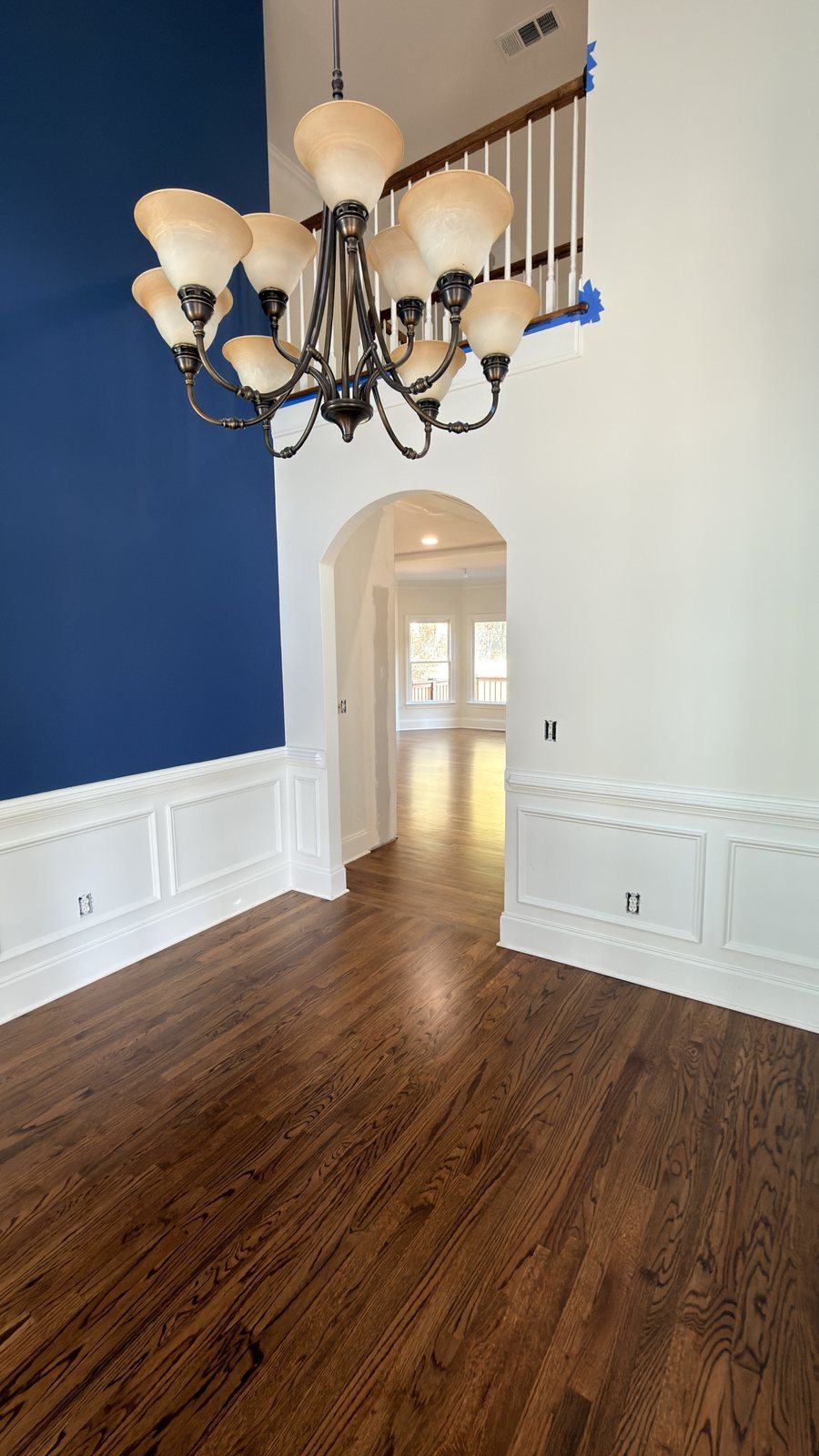 Entry hall with red oak hardwood floor in Honey stain and matte finish, chandelier, archway and navy accent wall
