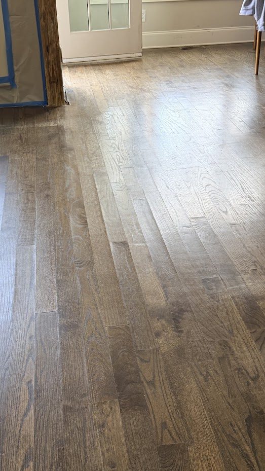 Gray-stained oak floor with raised board edges showing cupping across the room